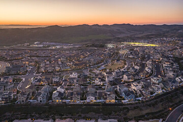 Aerial Summertime Sunset View Of Suburban Upscale California Neighborhood Community With Lit Baseball Field And Track Homes