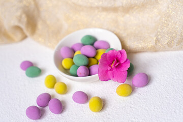 Colorful easter eggs and flower with plate on white desk. Top view, horisontal. Poster, mock up for design. Selective focus