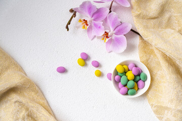 Colorful easter eggs and phalaenopsis orchid flower with plate on white desk. Top view, horisontal. Poster, mock up for design. Selective focus