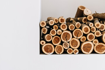 Chopped stacked firewood on a shelf in white wall. 