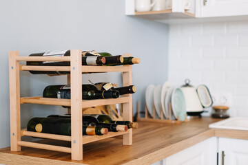 Wooden wine shelves with bottles on the table in modern kitchen. - Powered by Adobe