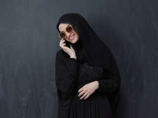 Young muslim businesswoman in traditional clothes or abaya using smartphone