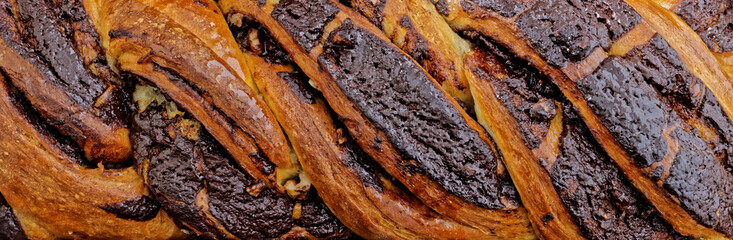 Braided cake with chocolate close-up view background. Yeast-risen dough twisted krantz cake top view.