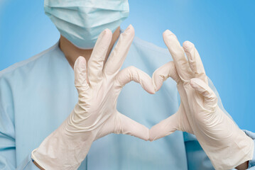 a doctor in a protective mask and gloves shows the heart with his hands. the cardiologist shows the...