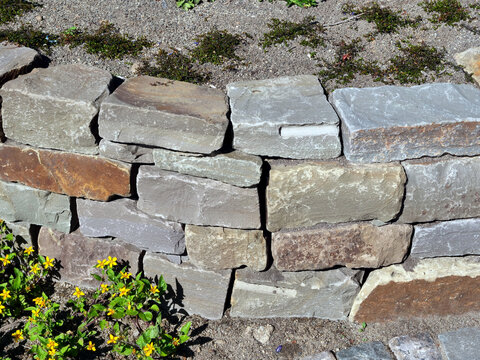 Kleine Bruchsteinmauer als Beetbegrenzung im Garten
