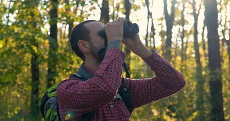 portrait of young male traveler with binoculars in the forest	