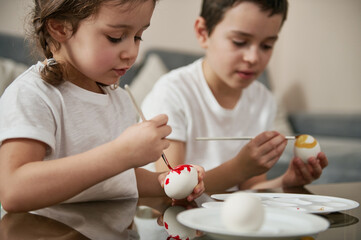 Children decorating eggs for Easter. Celebration of traditional religious event.