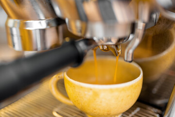 Making espresso drink on a professional coffee machine at home, close-up. Focus on a cup while pouring coffee.