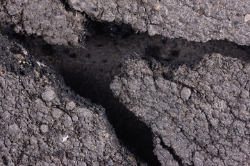 Fragment of black asphalt. Broken and cracked piece of old asphalt pavement.