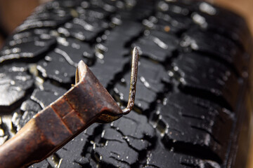 The mechanic pulled out the nail that punctured the tire of the car. Demonstration of a punctured wheel with a nail.