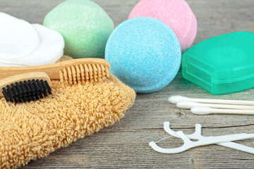 Tools for dental and body care on wooden background, close up. Bamboo toothbrushes, container of dental floss, toothpicks, ear sticks, bath bombs and towel. Рygiene concept.