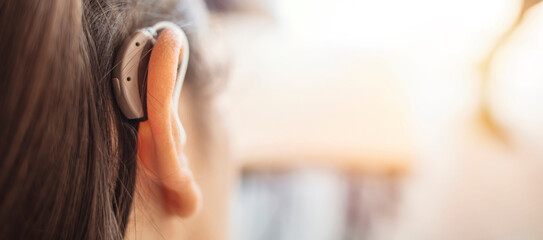 Deaf woman wearing hearing aid. Digital hearing aid in woman's ear. Brunette Woman with Modern...