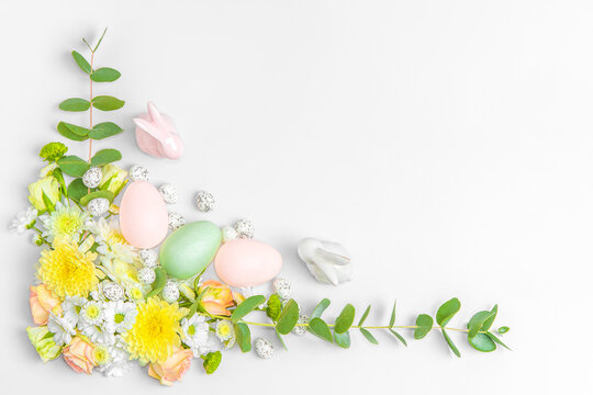 Creative layout composition of flowers and easter eggs on pastel background.