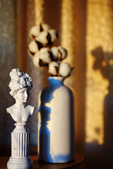 A small plaster antique female figure, her shadow and a vase with a cotton tree. In the style of monumentalism.