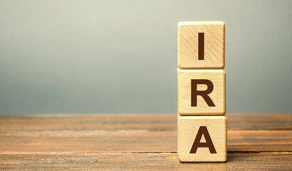Wooden blocks with the word IRA - individual retirement account. Tax-advantaged account that individuals use to save and invest for retirement. Business and finance concept