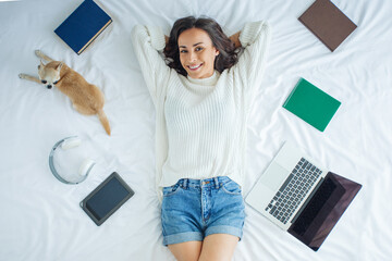 Above view portrait of happy smiling beautiful young woman relaxing on a bed after studying - Powered by Adobe