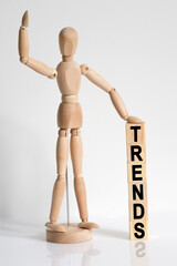 The wooden man raised his hand, and under his left hand he has cubes with the inscription - TRENDS