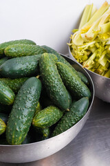 Vertical photo of two bowls with just washed cucumbers and celery.