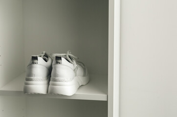 White sneakers on a white closet shelf.