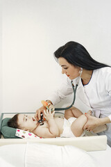 Doctor with stethoscope. Baby without clothes. Examination by a doctor.