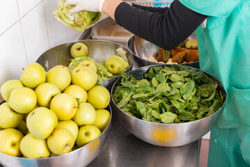 Green, fresh fruits, spinach leaves and vegetables in some metal big bowls.