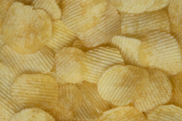 golden appetizing beautiful and rippled potato chips laid out evenly food background very close in detail