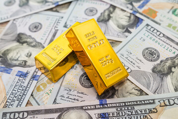 Two gold bars on the 100 US dollars banknote as a background.