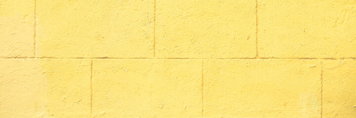 Plastered wall with decorative imitation of stone blocks. Weathered rough painted surface. Wide panoramic texture for background and design.