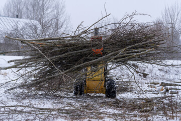 small stand-on mini skid steer with grapple full of wooden branches