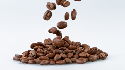 Falling Roasted Coffee Beans on White Background, close-up.