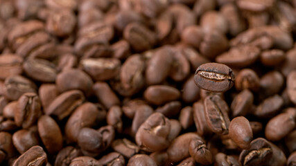 Falling Roasted Coffee Beans on Brown Background, close-up.