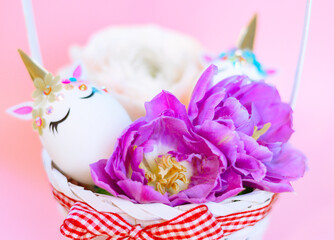 white Easter eggs decorated in the form of unicorns and flowers in basket on pink background, a minimal creative concept of a happy Easter
