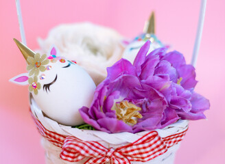 Easter eggs decorated in the form of unicorns and flowers in basket on pink background, a minimal creative concept of a happy Easter