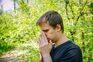 A man sneezes in a grove. Allergy concept