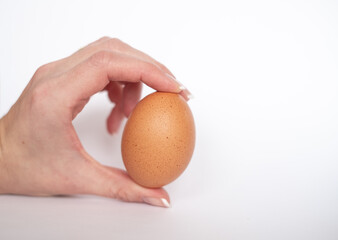 Fingers holding natural brown egg on white background. Breakfast food. Boiled egg.