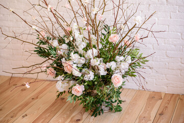 Decorations of branches with beautiful pink and white flowers in the basket against the background of a white brick wall