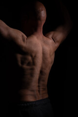 Fototapeta na wymiar Half naked muscular man with hands up and bold head on black background