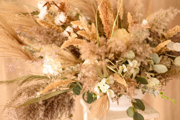 Decorations from dry beautiful flowers in a white vase on a beige fabric background