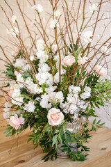 Decorations of branches with beautiful pink and white flowers in the basket against the background of a white brick wall