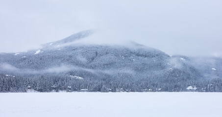 Obraz premium Beautiful View of Residential Homes in front of a frozen lake with Canadian Mountain Landscape in Background. Snowy Winter Day. Taken in Whistler, British Columbia, Canada.
