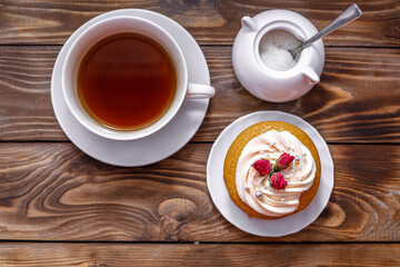 Sponge cake with cream, decorated with small flowers and a cup of tea.