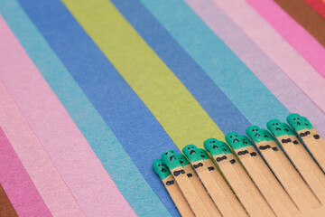 matchsticks with faces painted on the heads on multicolored paper
