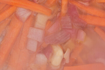 Carrot slices with red onions are fried in a cauldron on the grill