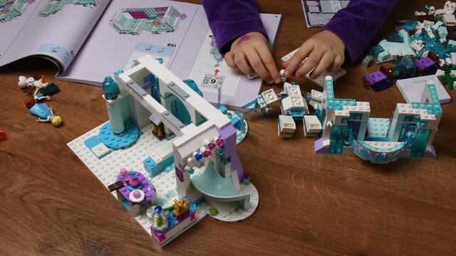 Kid hands play with plastic toy Lego snowman and construction blocks of Frozen Disney cartoon. Toddler girl fingers take and put toys in a row. Smart toys for education. Odessa, Ukraine, 12 06 2020