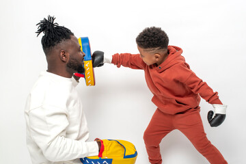 Dark skinned African male teaches his little son to box, isolated