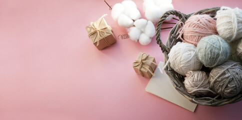 Basket with balls of thread. Gift boxes. Decorations for the holiday. Delicate colors, pink background.