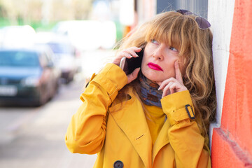 woman holding phone worried pensive on the street