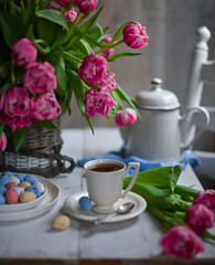 colorful eggs and rose tulips, cup of tea over white wood table