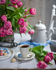 Obraz na płótnie Canvas colorful eggs and rose tulips, cup of tea over white wood table
