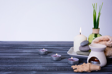 spa concept. zen stones, essential oil, candles and towel on a wooden background with space for text